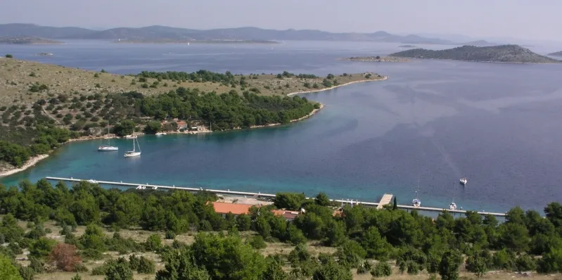 ACI Marina Žut from the hill above: the long pontoon along the shore of the bay, a few yachts at anchor and the Kornati islands beyond