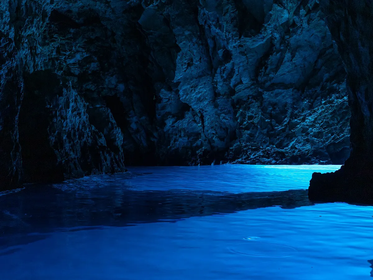 Light glowing blue on the water inside the Blue Cave (Modra špilja)