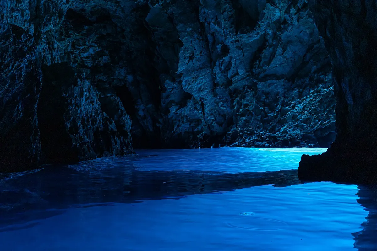 Light glowing blue on the water inside the Blue Cave (Modra špilja)
