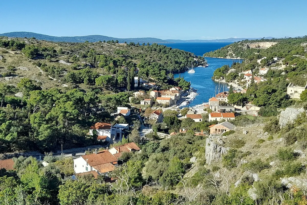 The Bobovišća inlet on Brač from the hill above, yachts moored along the narrow inlet below the village and the open sea beyond its mouth