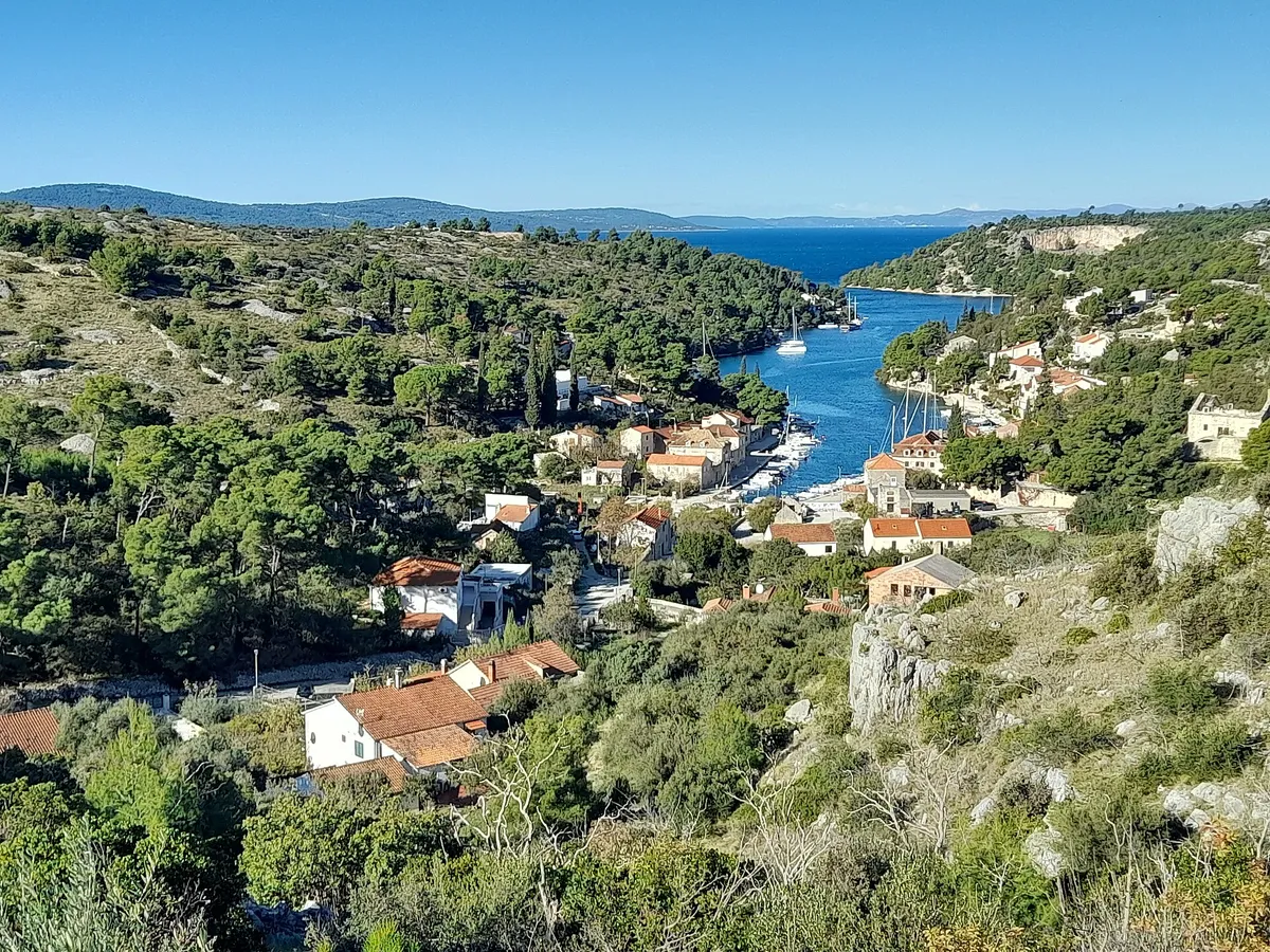 The Bobovišća inlet on Brač from the hill above, yachts moored along the narrow inlet below the village and the open sea beyond its mouth