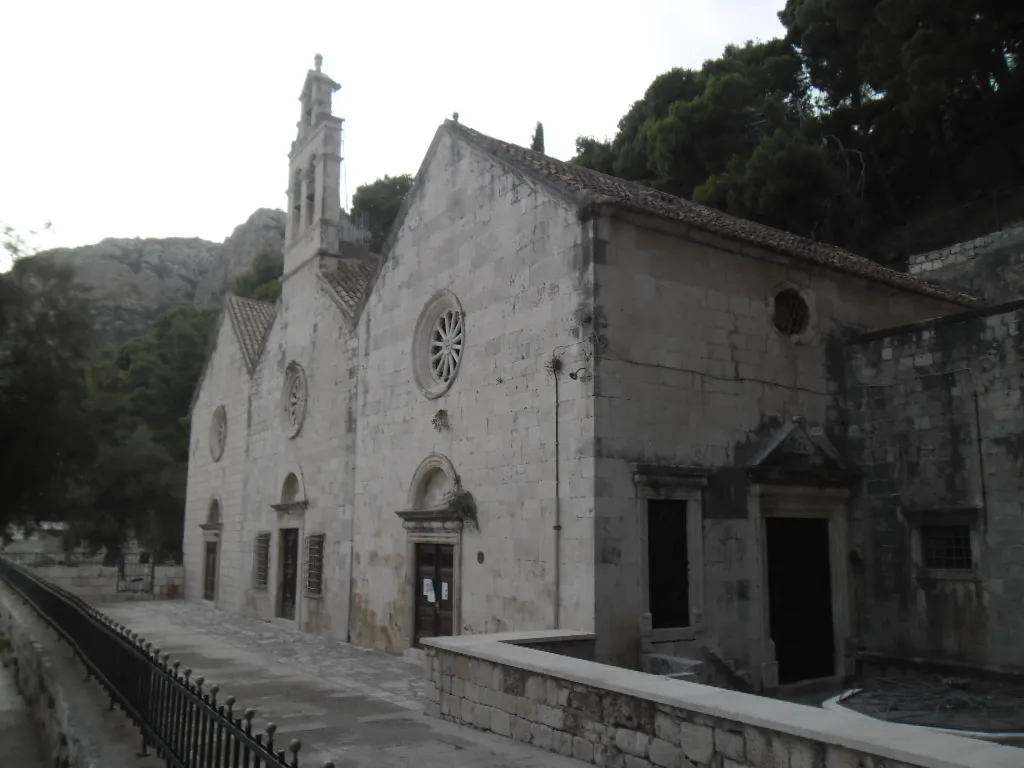 The church of Gospa Gusarica on the waterfront at the north end of Komiža bay, with the hills behind