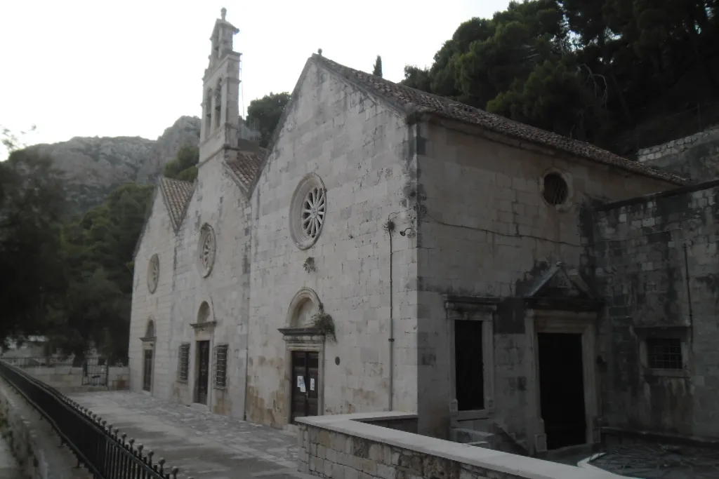 The church of Gospa Gusarica on the waterfront at the north end of Komiža bay, with the hills behind