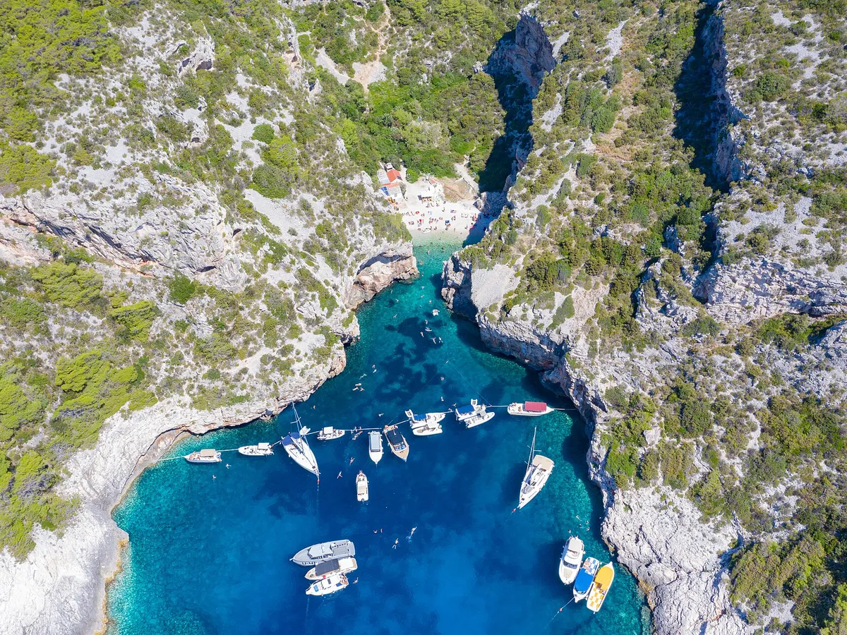 Yachts and motorboats anchored inside Stiniva cove, straight-down aerial