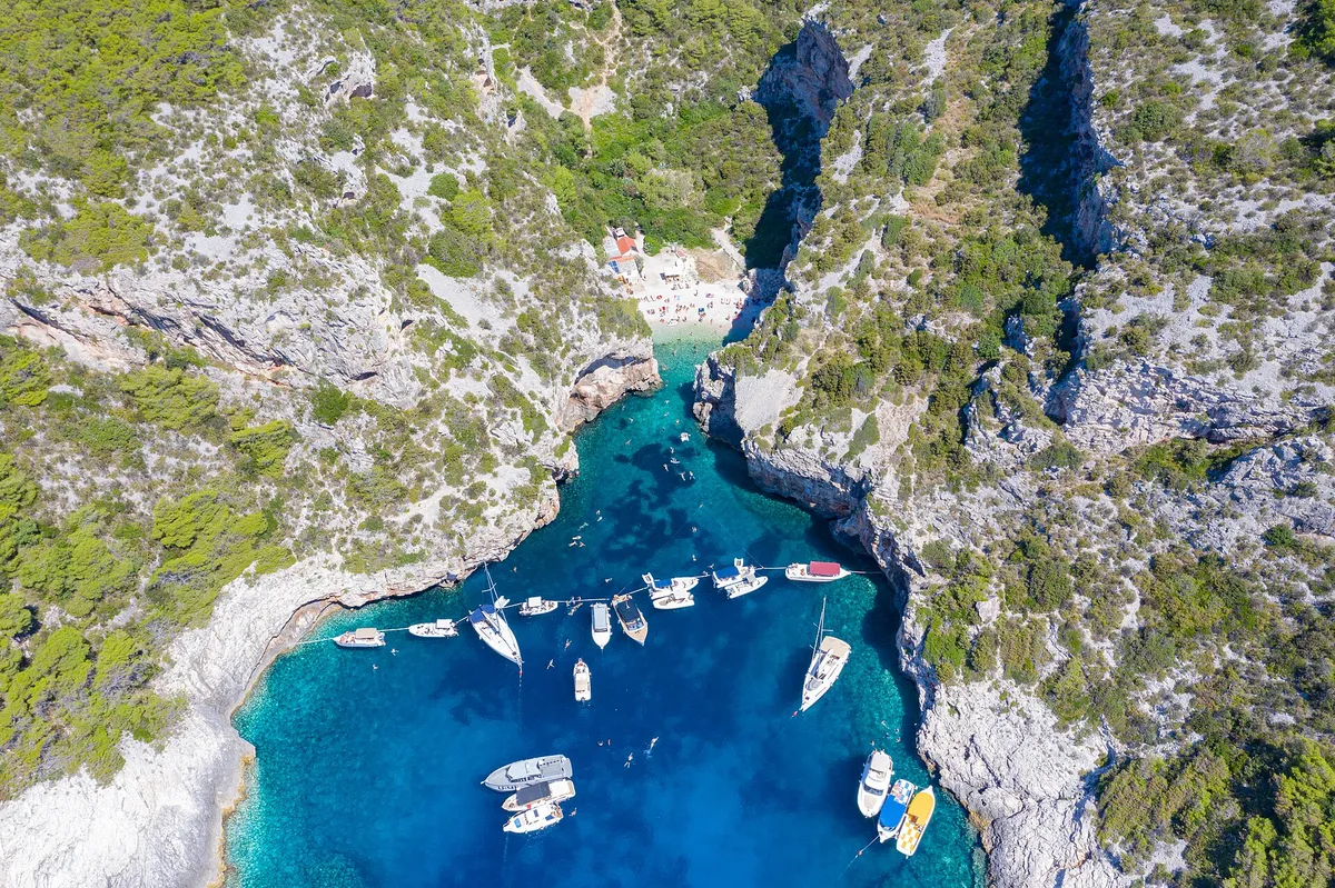 Yachts and motorboats anchored inside Stiniva cove, straight-down aerial