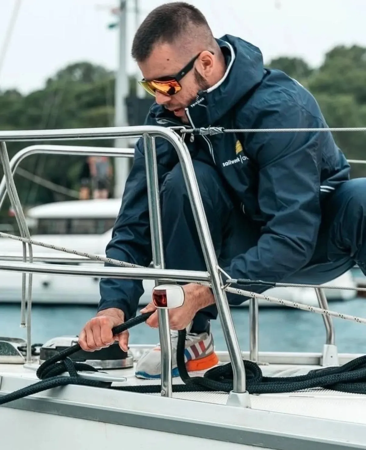 Ivor Benko on the foredeck of a yacht in harbour, working a mooring line at the bow cleat