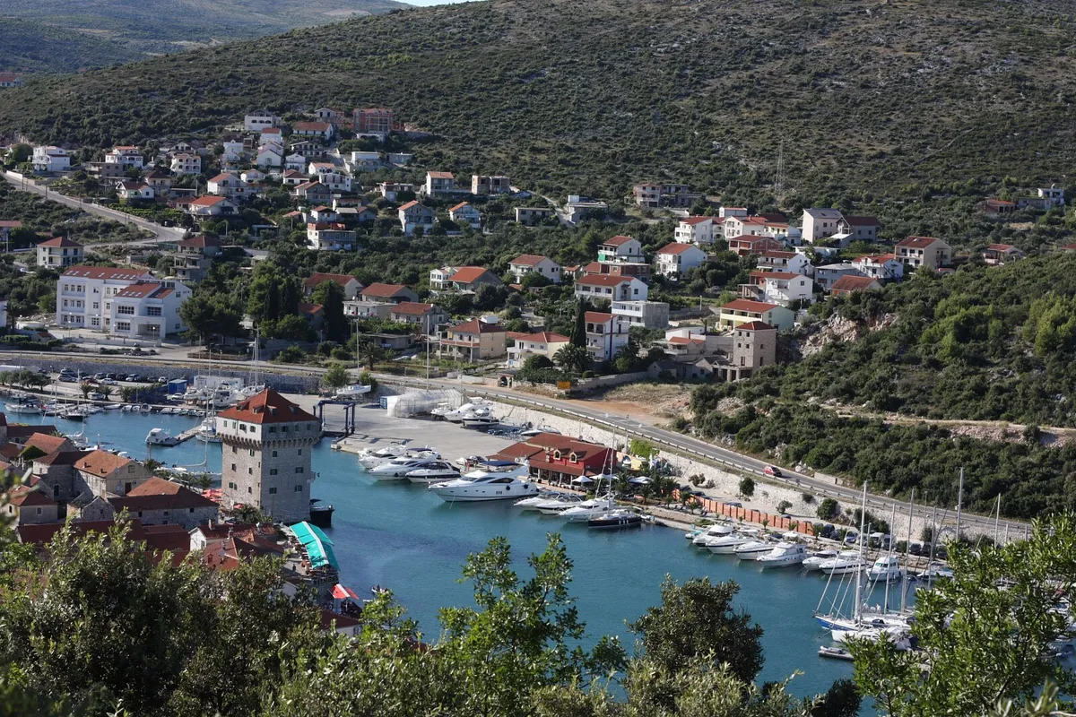 Marina Agana in Marina, west of Trogir, from the hill above: motor yachts and sailing yachts on the pontoons along the bay, the old tower on the waterfront and houses on the hillside