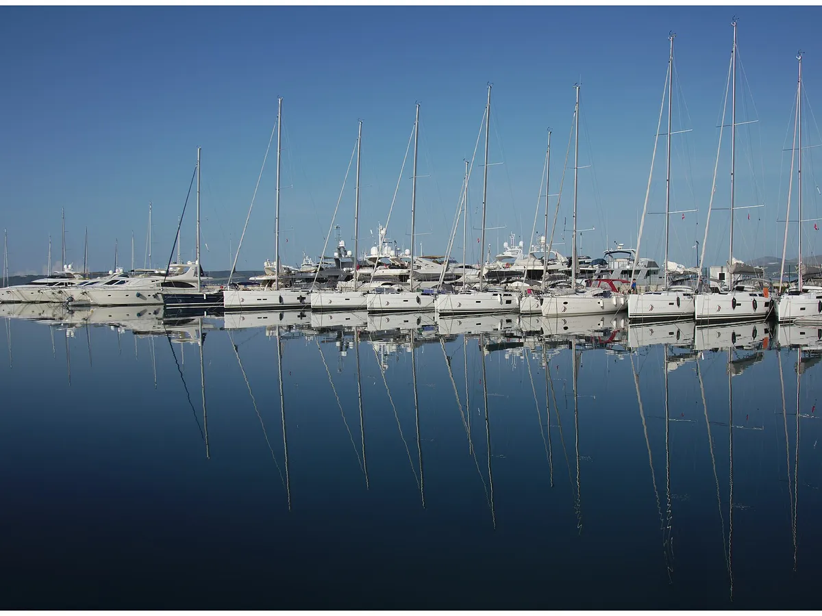 Rows of sailing yachts moored at Marina Kaštela in Kaštel Gomilica, their masts reflected in still water on a calm morning