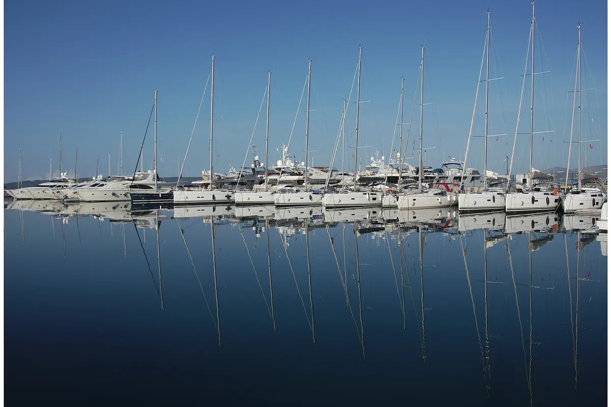 Rows of sailing yachts moored at Marina Kaštela in Kaštel Gomilica, their masts reflected in still water on a calm morning