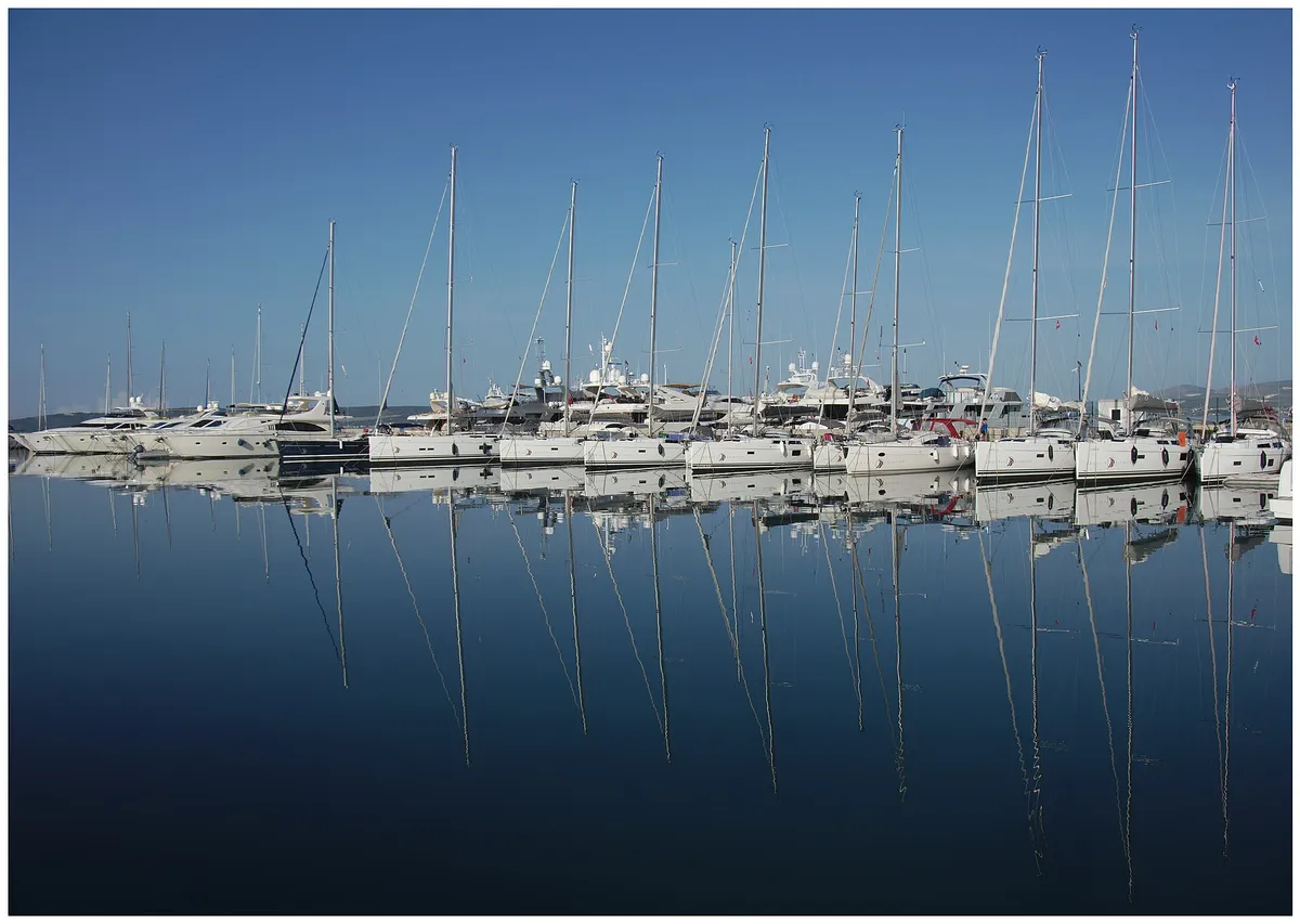 Rows of sailing yachts moored at Marina Kaštela in Kaštel Gomilica, their masts reflected in still water on a calm morning