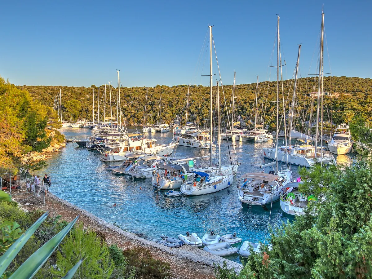 Yachts moored close together in the narrow Šešula bay beside Maslinica, late light