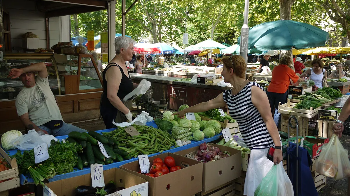 Vegetable stalls at Pazar, the green market in Split, with shoppers buying beans, cucumbers, cabbage and tomatoes under the trees