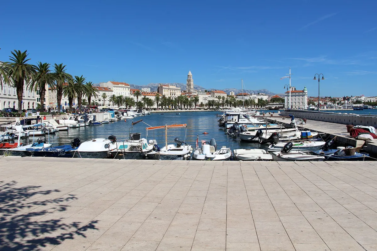 Small wooden and fibreglass boats in Matejuška, Split's old fishermen's harbour, with the Riva palms and the cathedral bell tower behind.