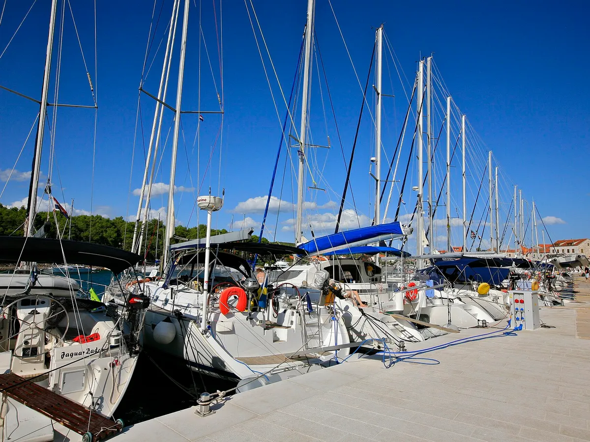 Visiting yachts moored stern-to along the town quay in Stari Grad, their passerelles down onto the stone quay, with the water and power posts along its edge