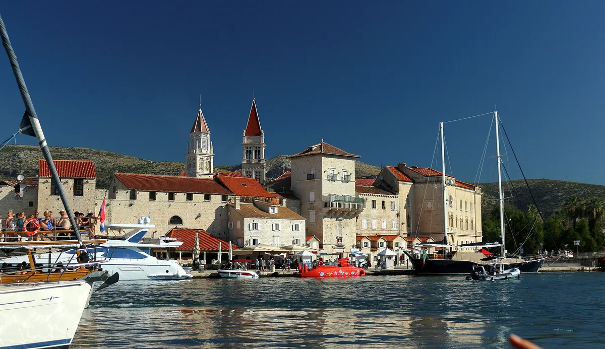 Trogir old town seen from a boat in the channel, with the cathedral and church towers, yachts and a gulet along the Riva.
