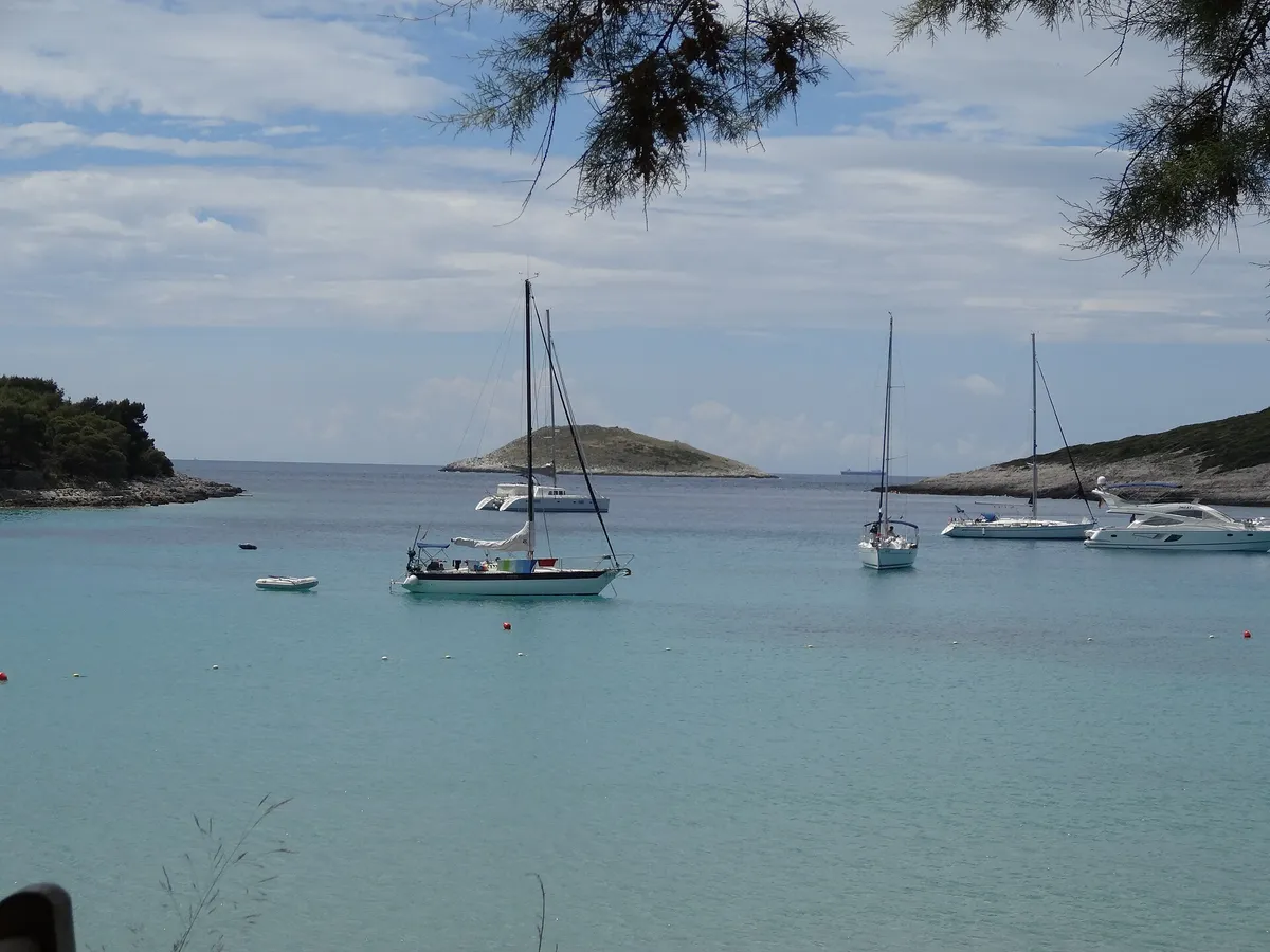Vinogradišće bay on Sveti Klement from the beach at its head, yachts on the buoys in pale turquoise water and the islet of Stambedar at the mouth