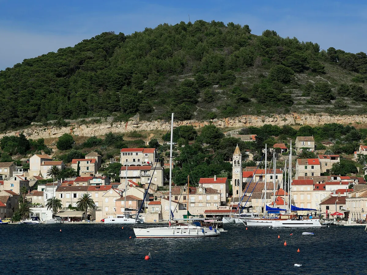 Kut waterfront in Vis town with yachts and gulets moored and a yacht on a buoy in front