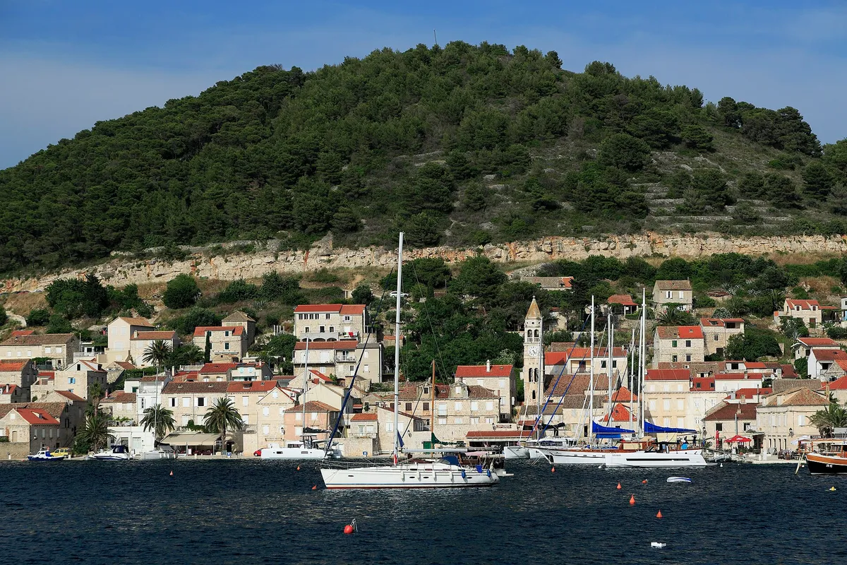 Kut waterfront in Vis town with yachts and gulets moored and a yacht on a buoy in front