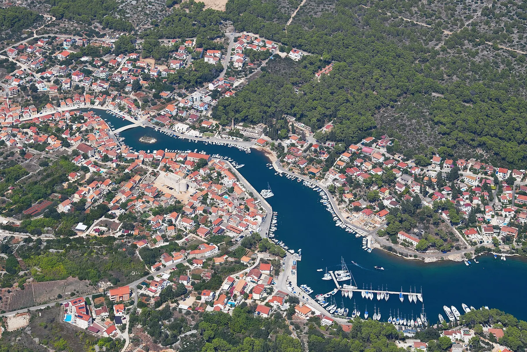Vrboska from the air: the long narrow bay running up into the village, its bridges and quays, and the marina pontoons of ACI Marina Vrboska near the mouth